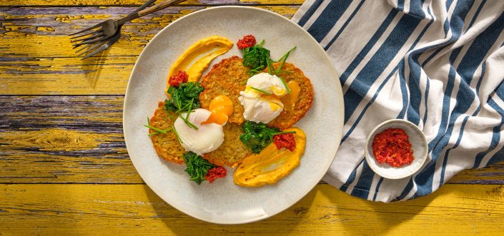 Placki z czosnkiem i majerankiem z duszonym szpinakiem, jajkiem w koszulce z patelni i sosem holenderskim z harissą