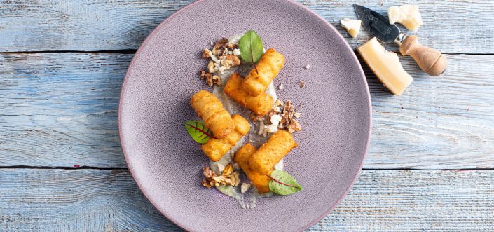 Картопляні крокети, подавані з соусом із чотирьох сирів і смаженими волоськими горіхами